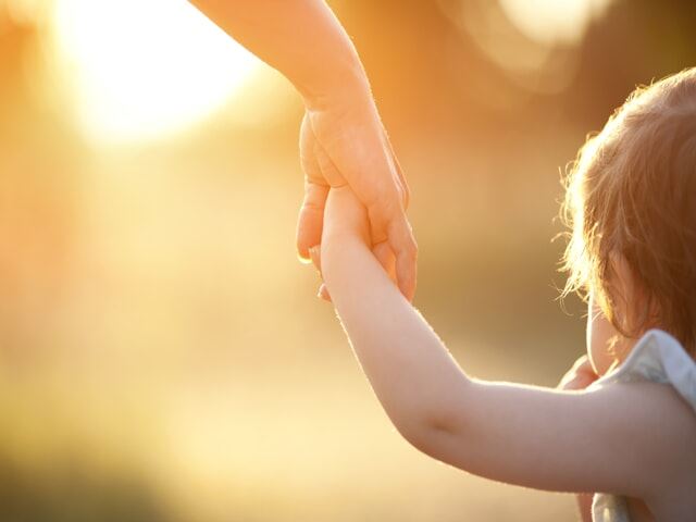 a parent with custody holds their small child's hand